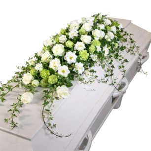 Vit kista dekorerad med en blomsterarrangemang av vita rosor och gröna blad.